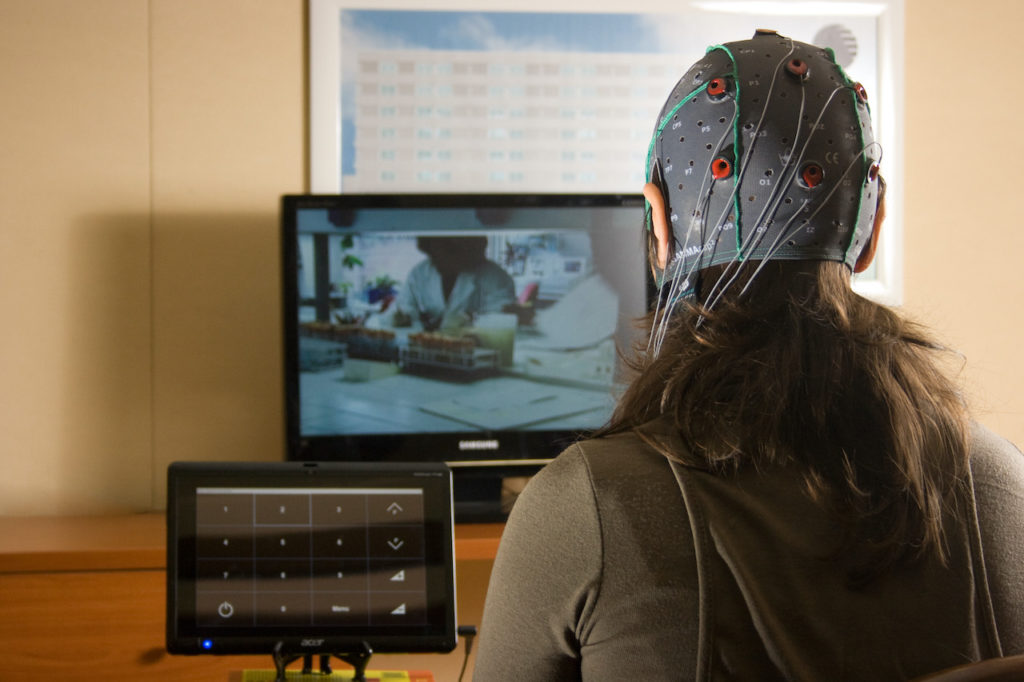 Personne équipée d'un casque souple d'électrodes devant un écran d'ordinateur