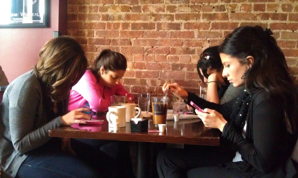 4 copines au café chacune rivée sur son smartphone